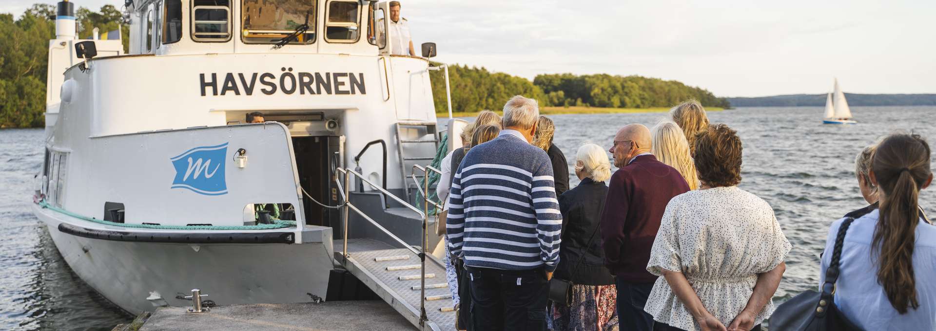 En grupp människor som står och inväntar ombordstigning på båten Havsörnen