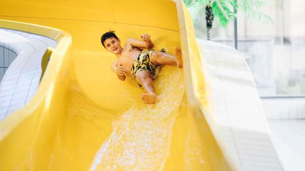 en pojke som åker nedför en gul vattenrutschbana